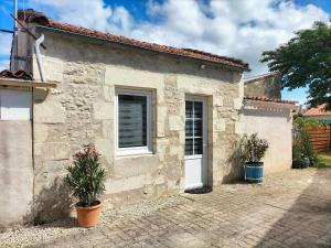 a stone house with two windows and two potted plants at agréable maison de vacances en Charente-Maritime in Arvert