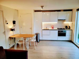 a kitchen with a wooden table and a kitchen with white cabinets at Bright room with kitchen in Amsterdam