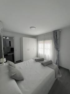 biała sypialnia z dwoma łóżkami i oknem w obiekcie Como en casa en el centro de Torrejón w mieście Torrejón de Ardoz