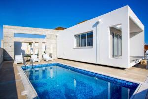 a villa with a swimming pool in front of a house at Villa Cerulean Paphos in Paphos City