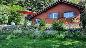 a house with a red umbrella in the yard at Chalet Idylka in Saignelégier