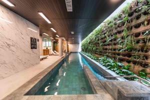 an indoor pool with plants on the wall at NK | Vila Mariana | Localização Perfeita in São Paulo