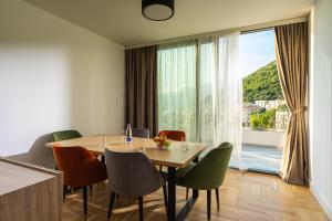 a dining room with a table and chairs and a large window at Vertmont Villa in Sveti Stefan
