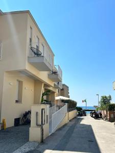 a building with a balcony and the ocean in the background at Hotel Perla in Castiglione della Pescaia