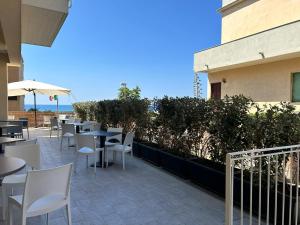 a patio with white chairs and tables and an umbrella at Hotel Perla in Castiglione della Pescaia