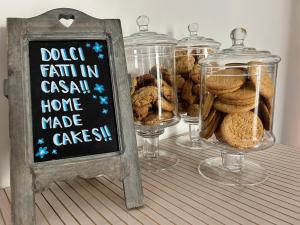 a table with three glass jars of cookies and a chalkboard at Hotel Perla in Castiglione della Pescaia