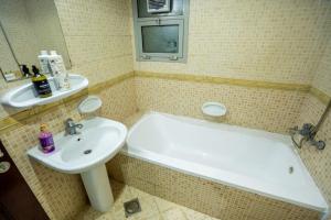 a bathroom with a sink and a bath tub and a sink at tourist Peaceful Family Rooms Abu Dhabi ME11APT baith al jannah LLC in Abu Dhabi