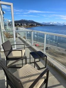 two chairs and a table on a balcony overlooking the water at Paraiso del lago in San Carlos de Bariloche