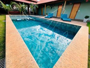 einen Pool mit blauen Stühlen neben einem Haus in der Unterkunft Recanto dos Sonhos - Rio Quente - Goiás in Rio Quente + 23 Fotos