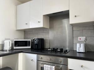 a kitchen with white cabinets and a microwave at Kilnview Guesthouse-Hanley & Staffordshire University in Stoke on Trent +10 photos