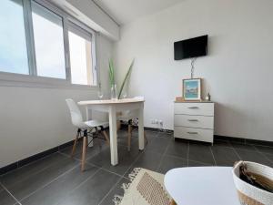 ein Wohnzimmer mit einem weißen Tisch und einem Fernseher in der Unterkunft la voile de mer - studio tout confort proche plage in La Rochelle + 2 Fotos