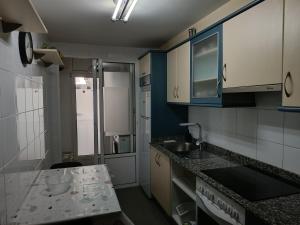 una cucina con armadi blu e bianchi e un lavandino di Recanto Milladoiro a O Milladoiro Altre 6 foto