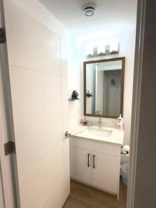 a white bathroom with a sink and a mirror at Stylish & Modern 2 Bedroom Suite in Regina