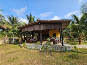 a small house with a porch with palm trees at Uzoma's Lodge in Butre