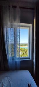 a bedroom with a window with a view of the ocean at Vito's Apartment in Ulëz