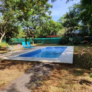 a swimming pool with blue chairs next to a yard at Tokai Surubi'i in Colonia Mariano Roque Alonso