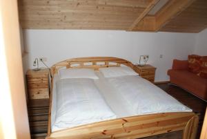 a bedroom with a wooden bed and a couch at Pension Wirt am Bach in Terento