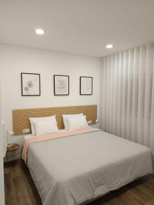 a bedroom with a large white bed with three pictures on the wall at Refúgio Vale da Pipa in Figueiró dos Vinhos