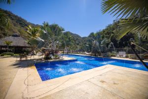 a swimming pool with blue water and palm trees at La Dulce Vista Hotel & Villas - Sierra Madre Puerto Vallarta in Puerto Vallarta