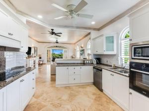 a kitchen with white cabinets and a ceiling fan at Tamarind Villa - Sugar Hill in Saint James