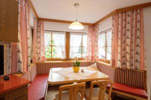 une salle à manger avec une table, des chaises et des fenêtres dans l'établissement Apartmenthaus DIAS, à Kappl