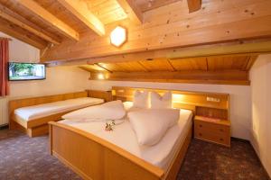 deux lits dans une chambre avec plafonds en bois dans l'établissement Apartmenthaus DIAS, à Kappl