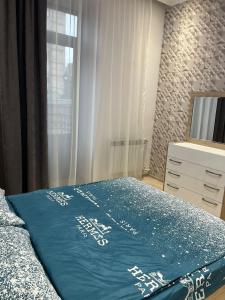 a bedroom with a bed with a blue blanket on it at Apartment in the city center on Bagramyan avenue 23 in Yerevan
