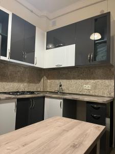 a kitchen with black and white cabinets and a wooden table at Apartment in the city center on Bagramyan avenue 23 in Yerevan +1 photo