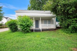a small white house with a porch in the grass at Quiet Family Home - Downtown, Pet Friendly, 4 Beds in Raleigh