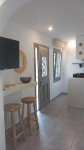 a kitchen with a table and two stools and a tv at Sails1 in Agia Eleousa