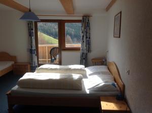 two beds in a room with a window at Pension Wirt am Bach in Terento