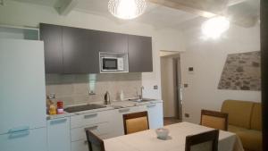 a kitchen with white cabinets and a table with chairs at Bardi al Riolo Betulla appt in Bardi