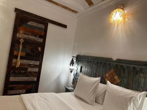 a bedroom with a bed with white sheets and a chandelier at Dar Rihana Dadès in Aït Idaïr