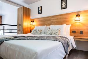 a bedroom with a white bed with a wooden headboard at Central Suites by H&R in Villeta