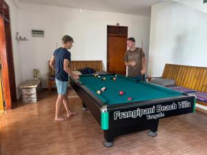 two men playing pool in a room with a pool table at Frangipani Beach Villa in Tangalle
