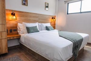 a bedroom with a large white bed with a wooden headboard at Central Suites by H&R in Villeta