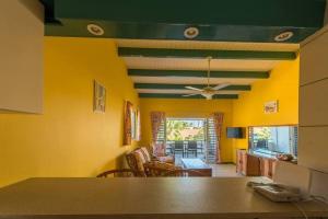 a living room with yellow walls and a ceiling with a ceiling fan at Club Seru Coral Trupial in Willemstad
