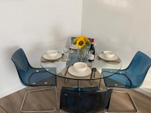 a glass table with blue chairs and a vase of flowers at Luxury One Bedroom Apartment in Borehamwood-Free Parking in Borehamwood