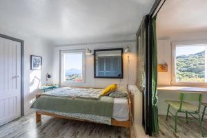 a bedroom with a bed and a desk and two windows at Loft en Tarifa con vistas a África in Tarifa