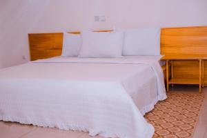 a white bed with a wooden headboard and a desk at Green Villa Apartments in Kigali