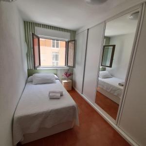 APARTAMENTO ZAPILLO ALMERIA 100 METROS DE LA PLAYA في ألميريا: غرفة نوم بها سرير ومرآة كبيرة