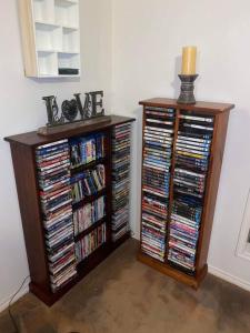 a room with two book shelves filled with dvds at Family home close to Melb Airport, free FAST WIFI! in Craigieburn +17 photos
