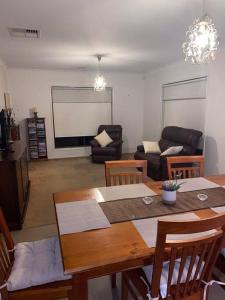 a living room with a wooden table and chairs at Family home close to Melb Airport, free FAST WIFI! in Craigieburn