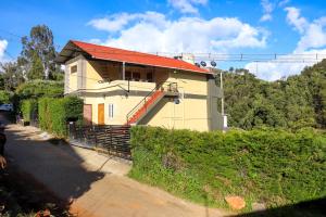 uma casa amarela com um telhado vermelho numa rua em Themapleview em Ooty