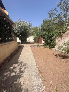 a walkway next to a building with trees and a wall at Villa pour Location de Vacances in Imouzzer Kandar