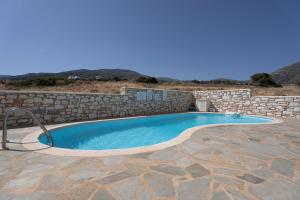 a swimming pool with a stone retaining wall and a stone at Maisonette San Tosa in Aspro Chorio Paros