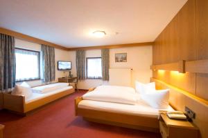 a hotel room with two beds and two windows at Garni Mathonerhof in Ischgl