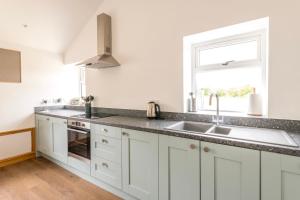 a white kitchen with a sink and a window at Well-located countryside cottage in Nailsea