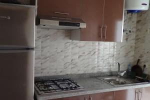 a kitchen with a sink and a stove top oven at Appartement à Cap de l'eau, vue piscine in Ras El Ma