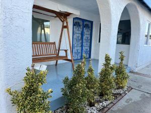 Un porche con una silla y árboles frente a una puerta. en Entire home in Lawndale Los Angeles, en Lawndale